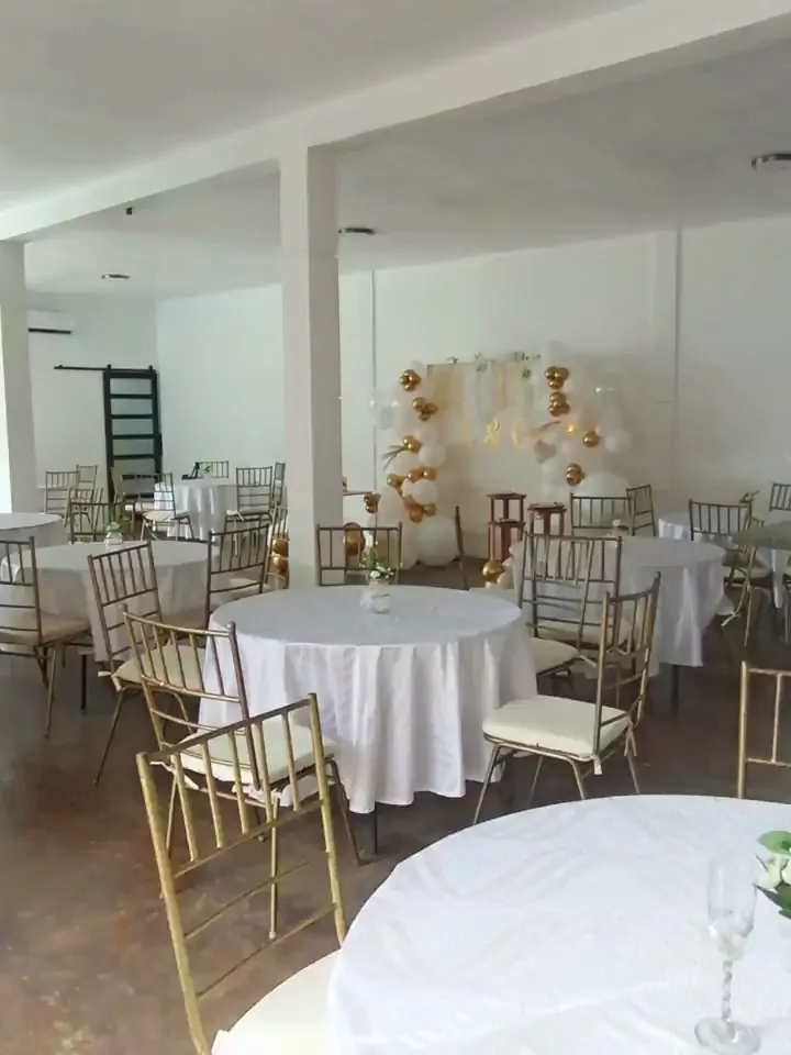 Área techada de La Huerta montada con mesas redondas y sillas doradas